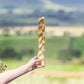 a hand holding a beef braid dog treat